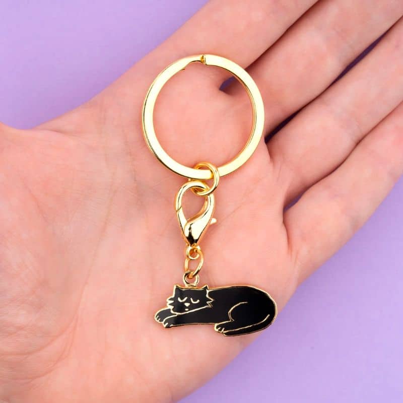 porte-clé médaille en forme de chat noir avec détails dorés