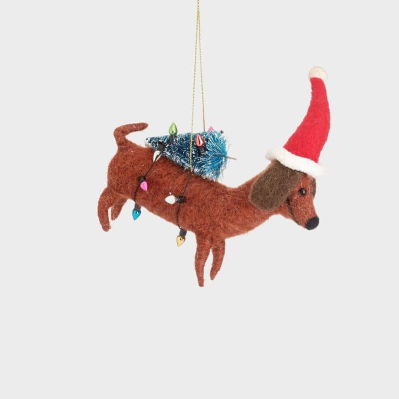 Boule de noël en feutrine qui représente un chien teckel saucisse avec un sapin de Noël de la marque Sass and Belle
